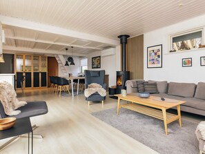 Ein modernes Wohnzimmer mit Kamin, eine Essecke mit Treppe und eine Küche mit Holzschränken.