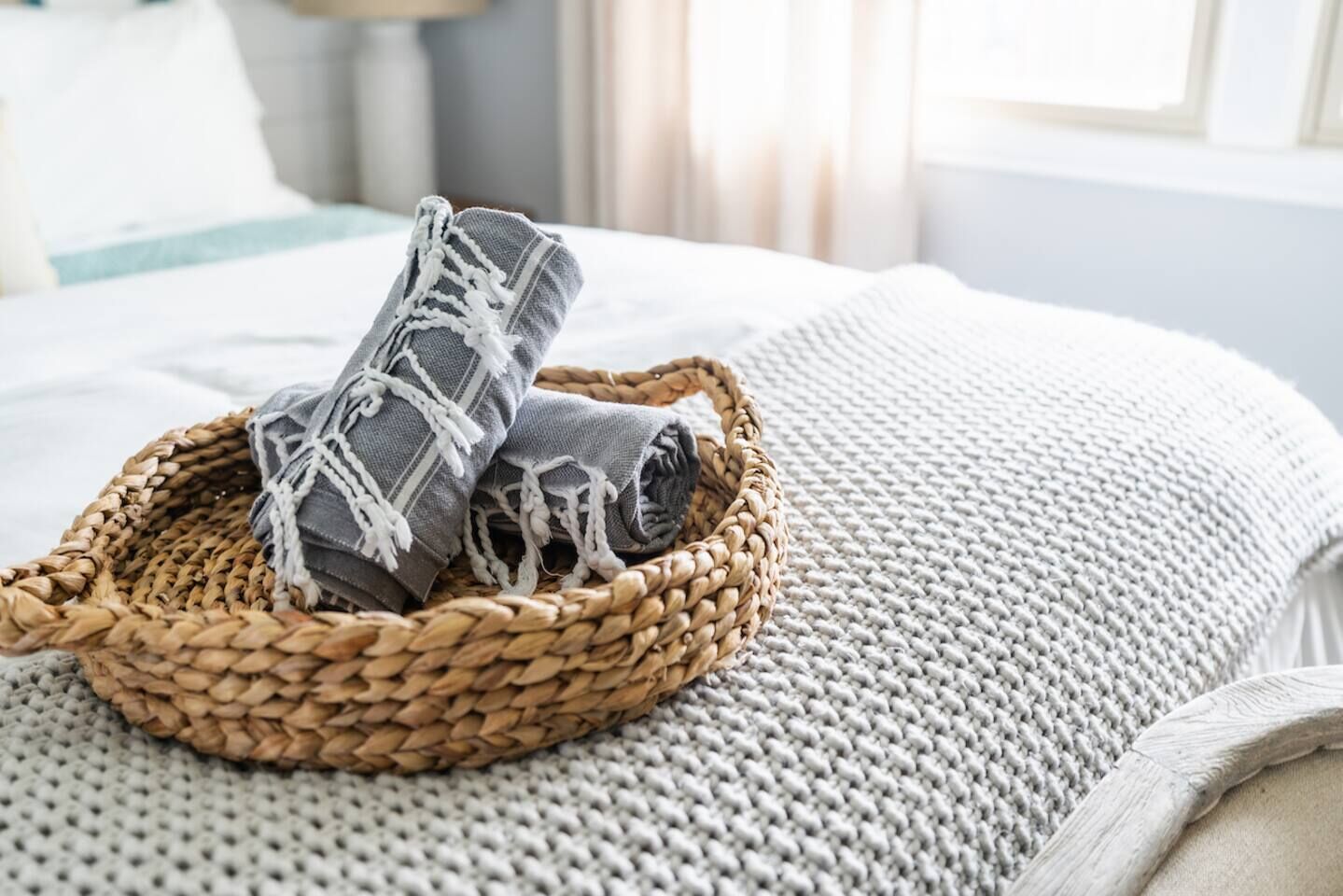 A woven basket with a rolled-up item on a textured blanket.