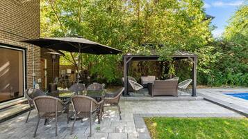 A patio with outdoor furniture, a pergola, and a swimming pool.