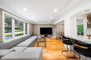 A modern living room with a sofa, TV, and dining area.
