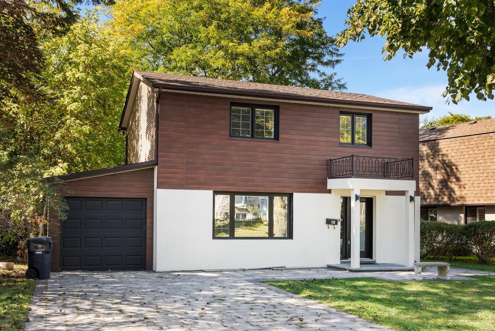 A two-story house with a garage, a balcony, and a paved driveway.