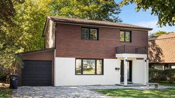 A two-story house with a garage, a balcony, and a paved driveway.