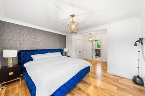 Ein Schlafzimmer mit einem großen Bett, einem Nachttisch, einer Lampe, einer Deckenleuchte und einem Staubsauger.