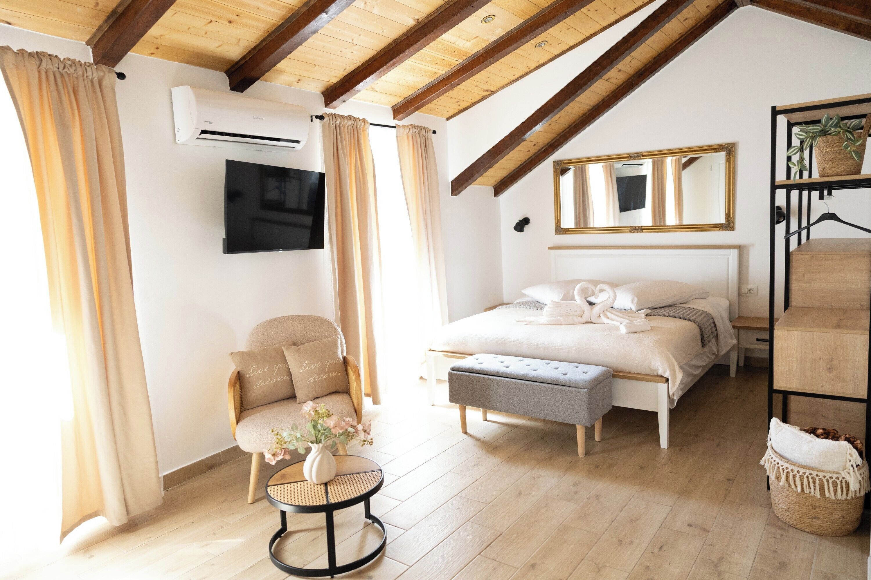 Een slaapkamer met een bed, een stoel, een klein tafeltje met bloemen, een airconditioning en een spiegel aan de muur.