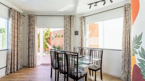 A dining area with a glass table and chairs, curtains, and a view of the outdoors.