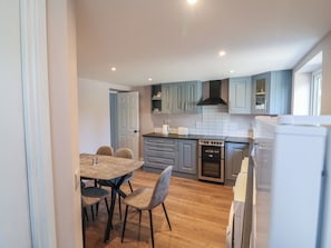 A modern kitchen with grey cabinets, a wooden dining table with chairs, and a built-in oven. - ABINA'S, family friendly, with a garden in Kenmare, County Kerry (Kenmare)