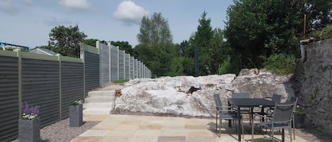 A patio area with stone flooring, a table with chairs, and a stone wall.