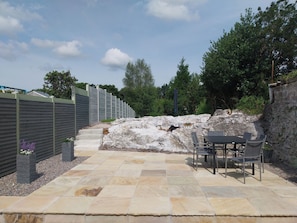 A patio area with stone flooring, a table with chairs, and a stone wall. - ABINA'S, family friendly, with a garden in Kenmare, County Kerry (Kenmare)