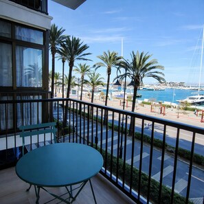 Ein Balkon mit Tisch, der auf einen Yachthafen mit Booten und Palmen blickt.
