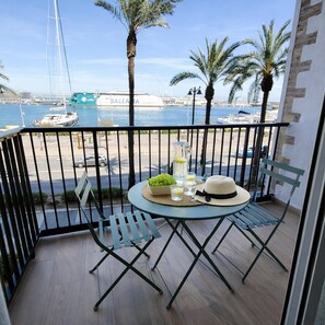 Ein Balkon mit einem Tisch für zwei Personen, komplett mit einer Flasche, Gläsern und einem Obstkorb.