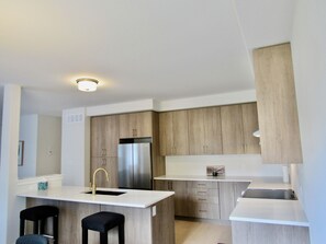 Uma cozinha moderna com ilha central, eletrodomésticos de aço inoxidável e armários de madeira.