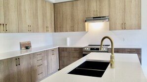 A modern kitchen with wooden cabinets, a stainless steel range, and a gold faucet.