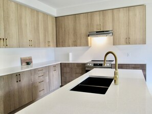 A modern kitchen with wooden cabinets, a stainless steel range, and a gold faucet.