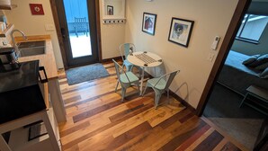 A compact living space with a kitchenette, a dining area with a table and chairs, a small seating area with a sofa, and a window with a view.