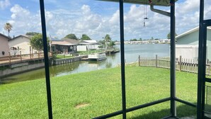 A view of a canal with a boat docked on the right, surrounded by grassy areas and residential buildings. - The Burnside Bungalow where Vacation Awaits! (Holiday)