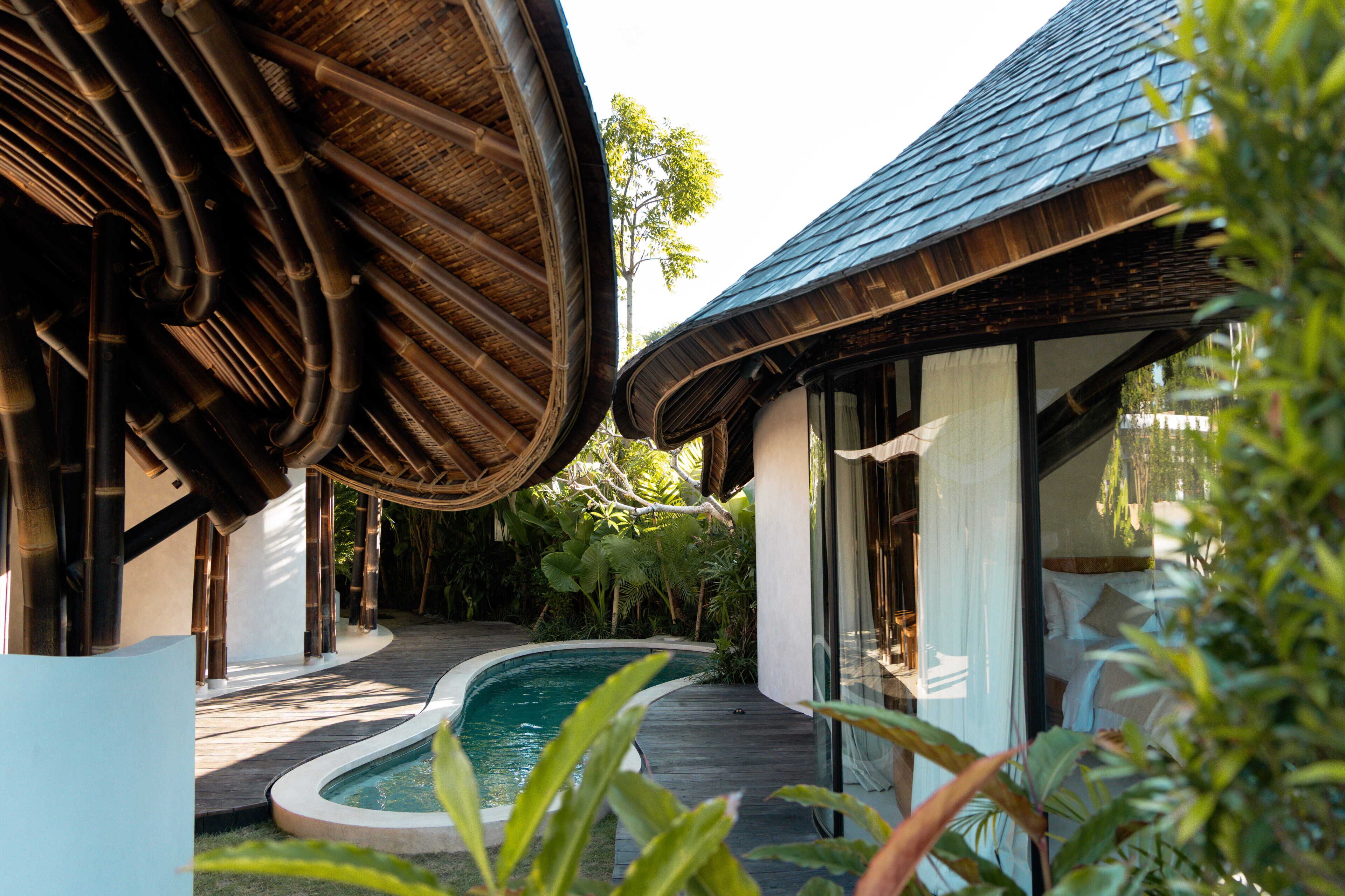 Um edifício moderno com teto curvo, piscina e porta de vidro que dá para um quarto.