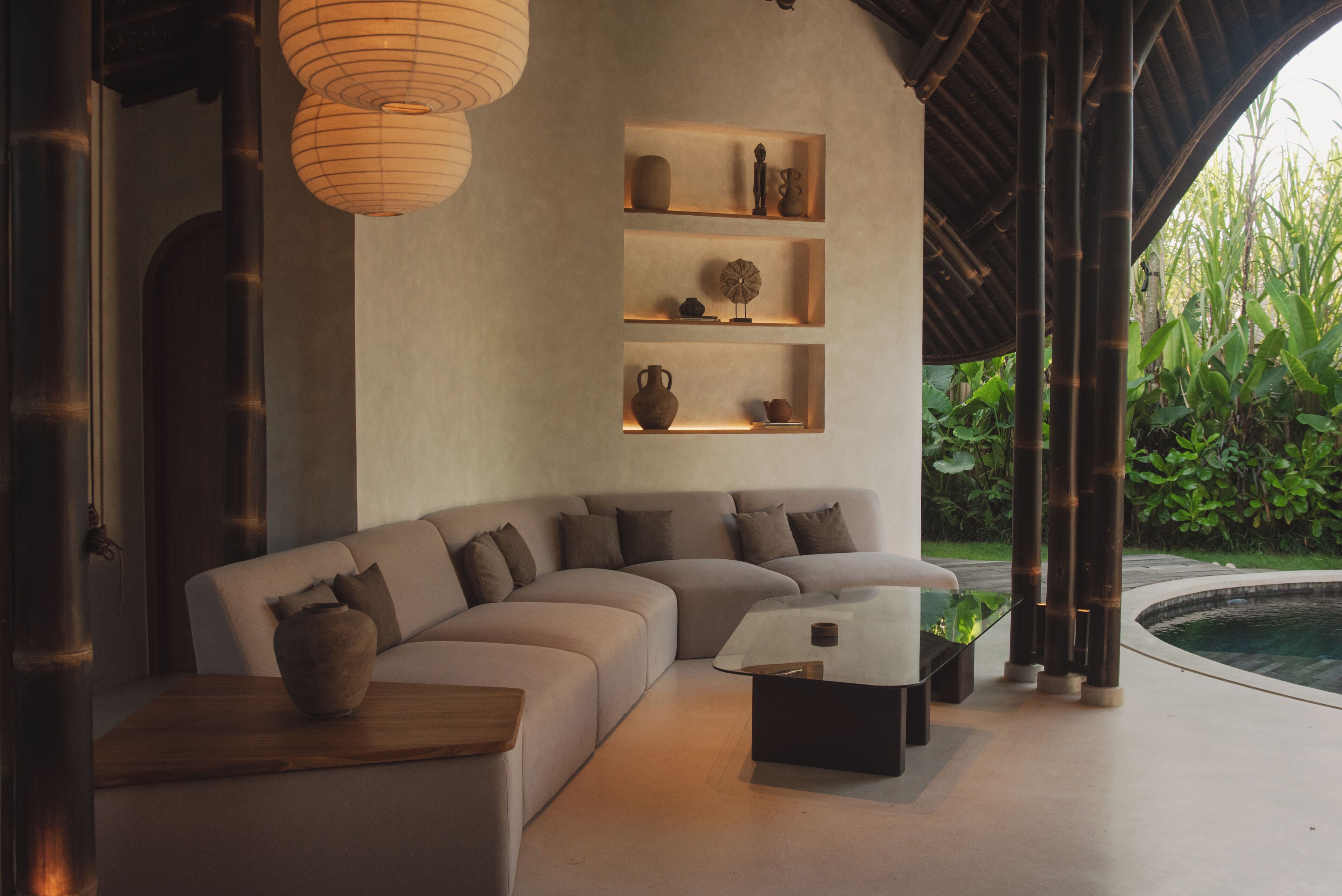 Una sala de estar moderna con un sofá curvo, una mesa de centro y estantes con objetos decorativos.