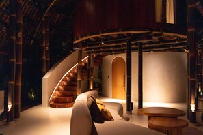 A modern interior with a curved staircase, a sofa, and a round table. - Kaymana (Pecatu)