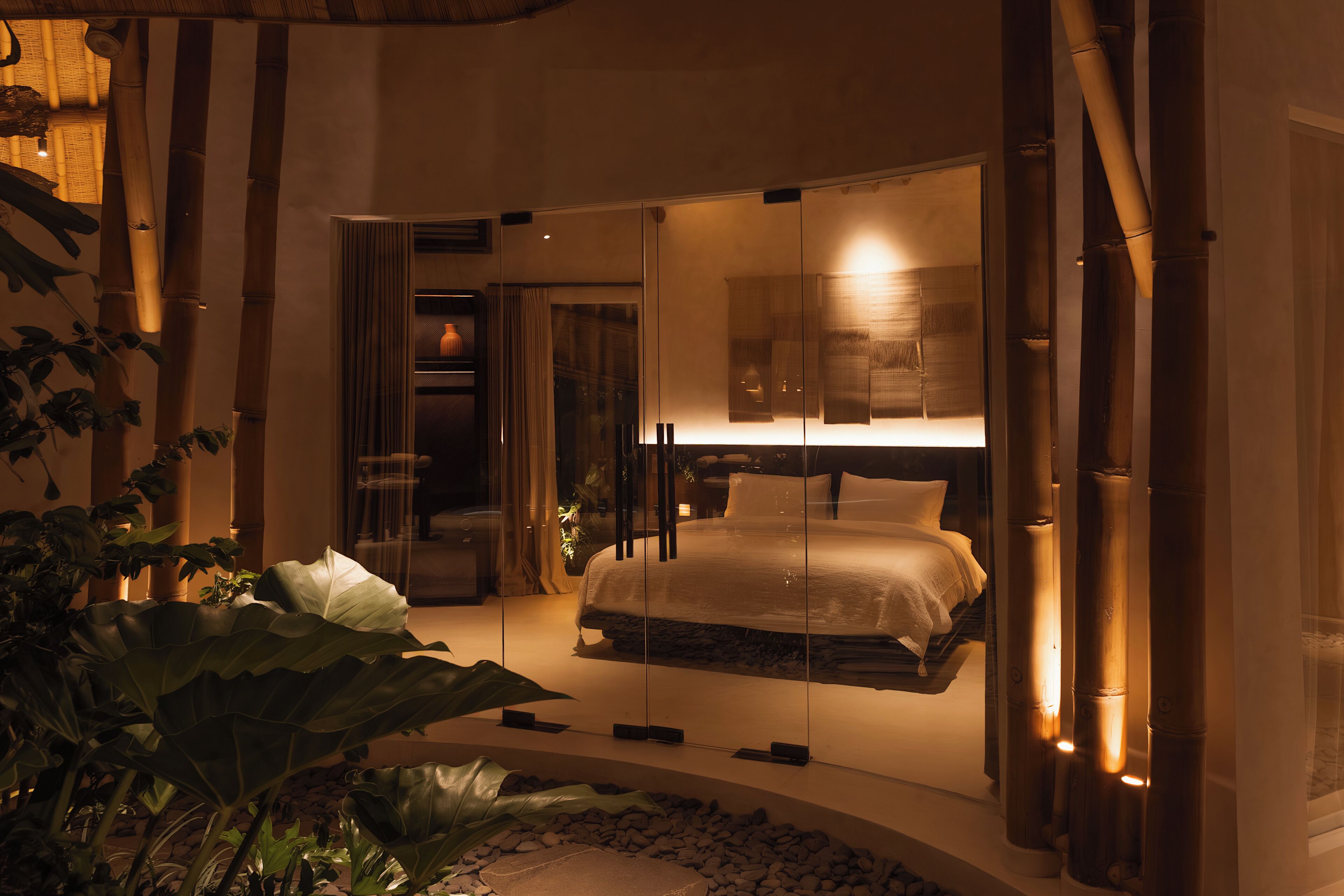 Un dormitorio con cama, separador de vidrio y vista al baño.