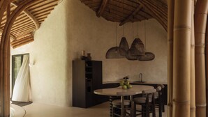 A modern kitchen with a round dining table, hanging wicker light fixtures, and a bamboo ceiling. - Kaymana (Pecatu)