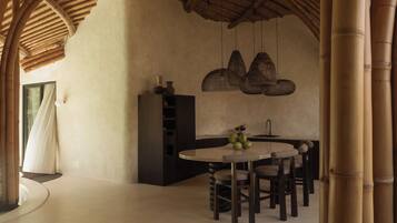 A modern kitchen with a round dining table, hanging wicker light fixtures, and a bamboo ceiling.