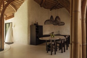 Une cuisine moderne avec une table à manger ronde, des luminaires suspendus en osier et un plafond en bambou.