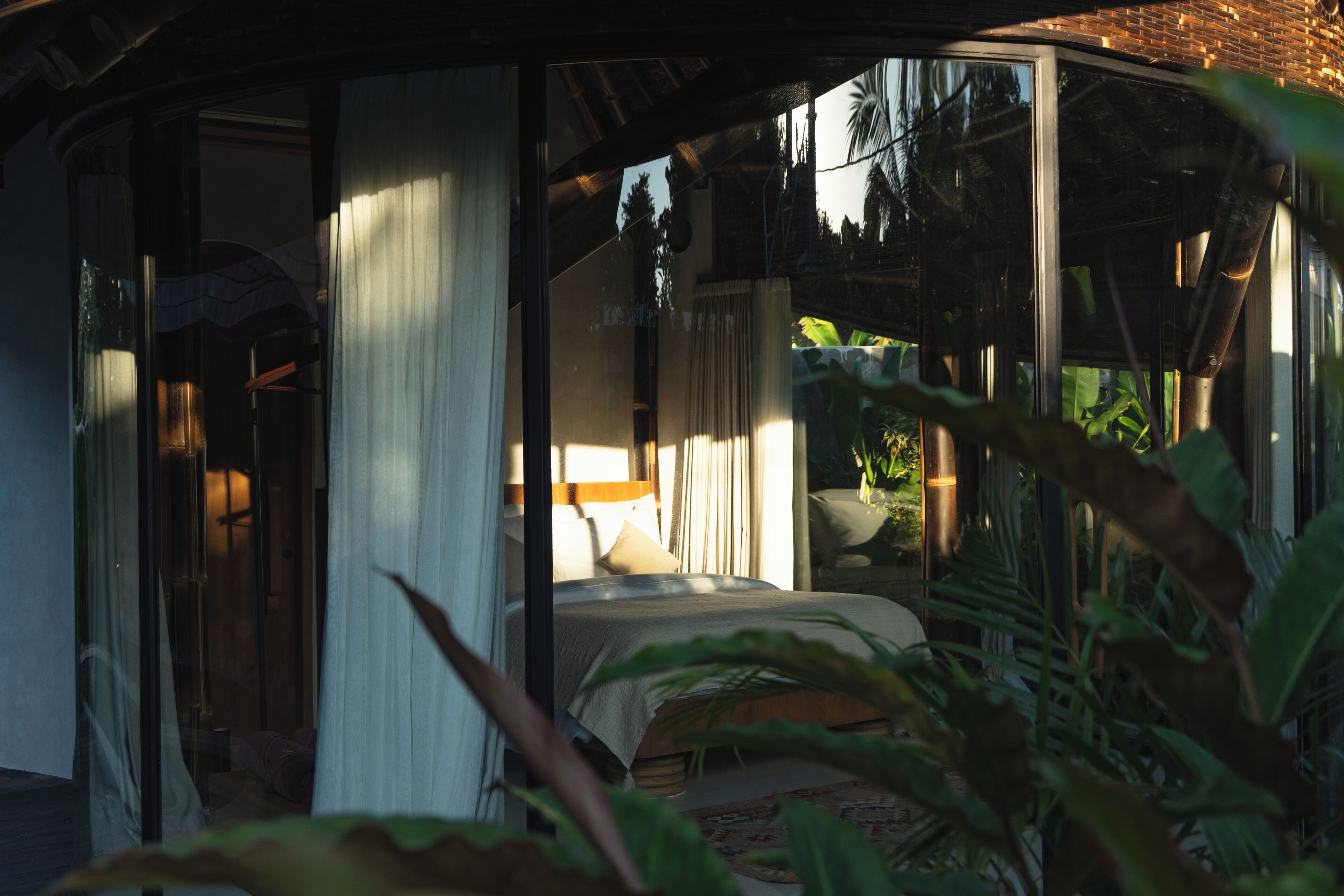 A room with a bed, curtains, and a view of the outdoors.