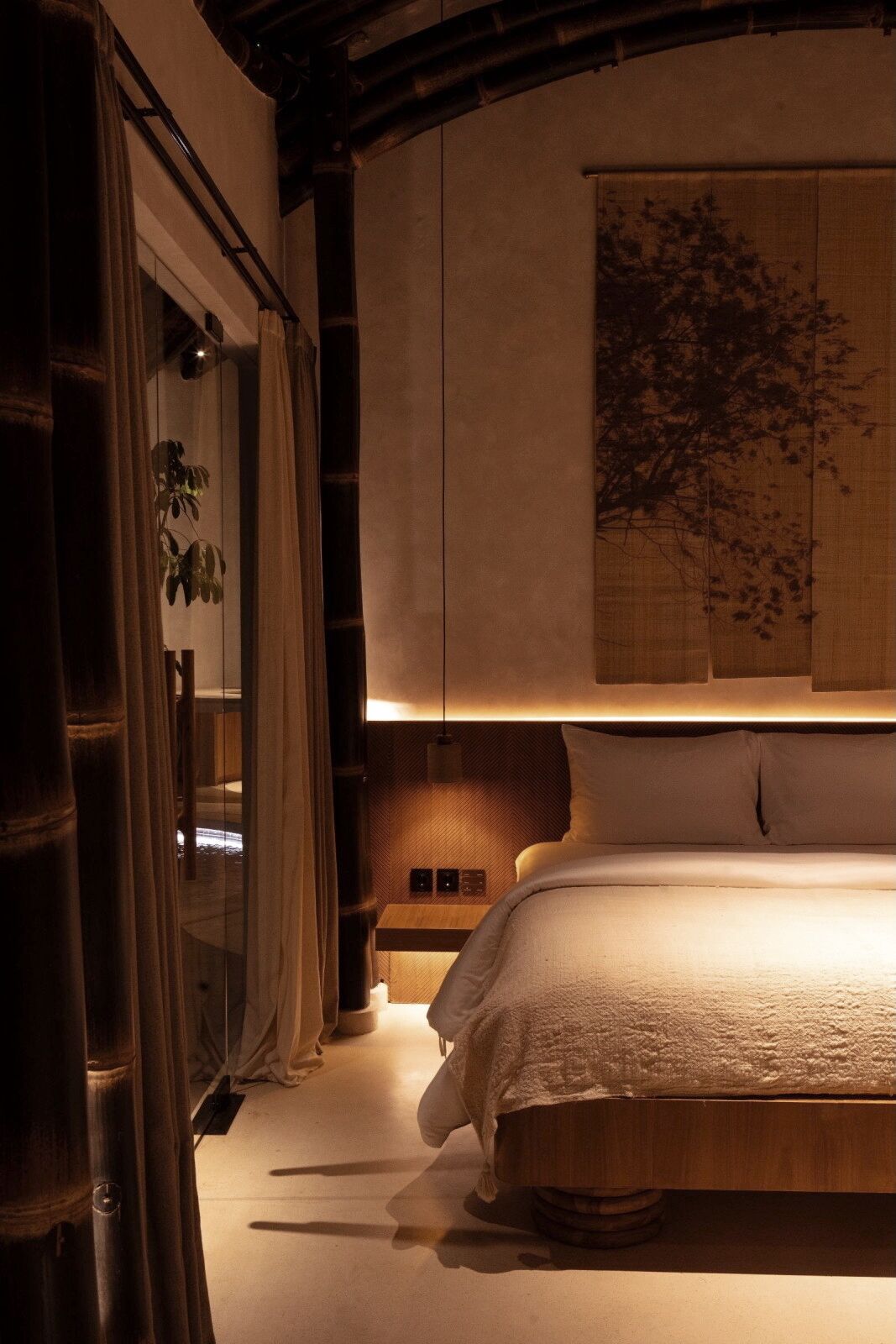 A bedroom with a bed, curtains, a wall-mounted artwork, and a bedside table.
