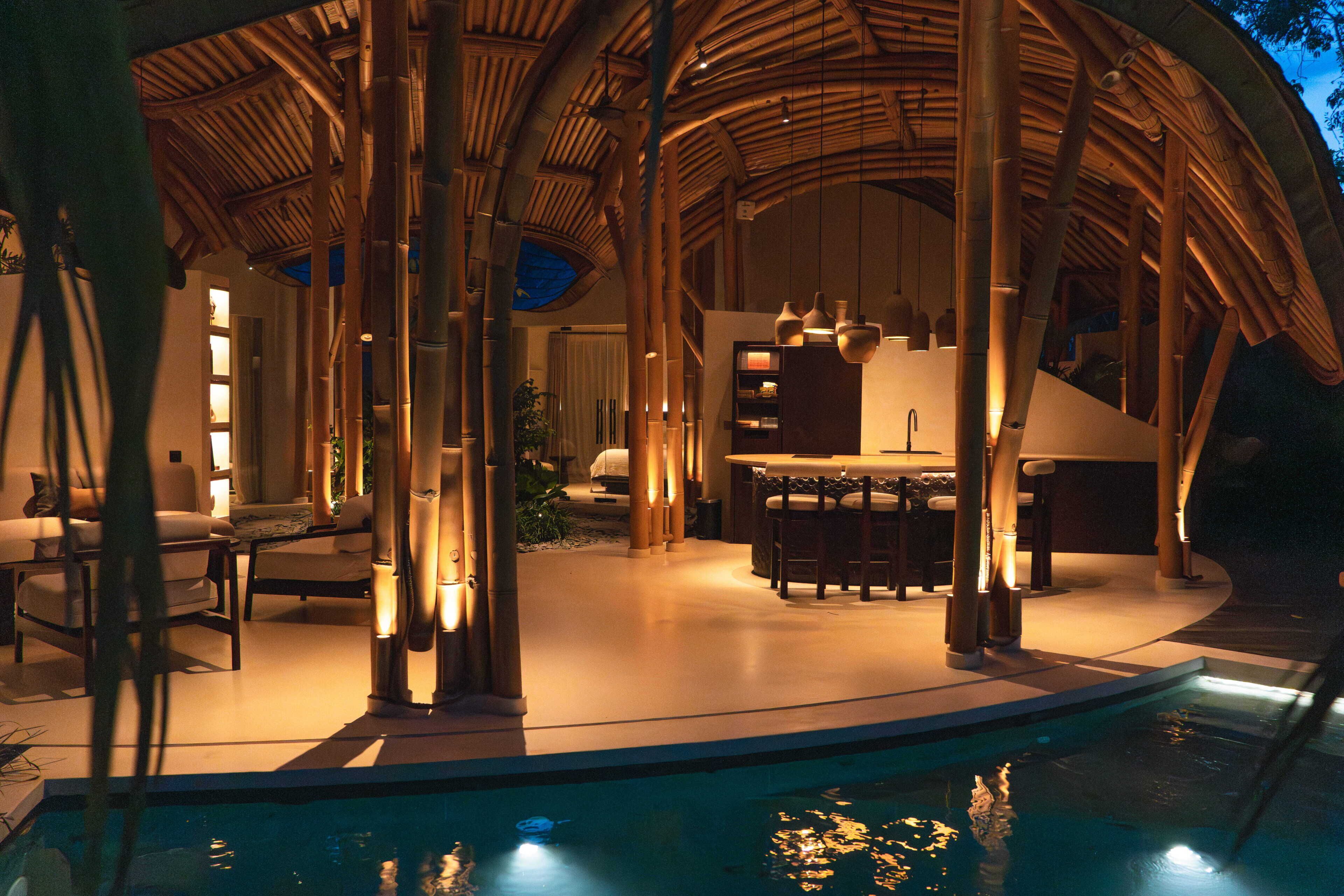 A poolside area with a bamboo structure, seating, and a bar.