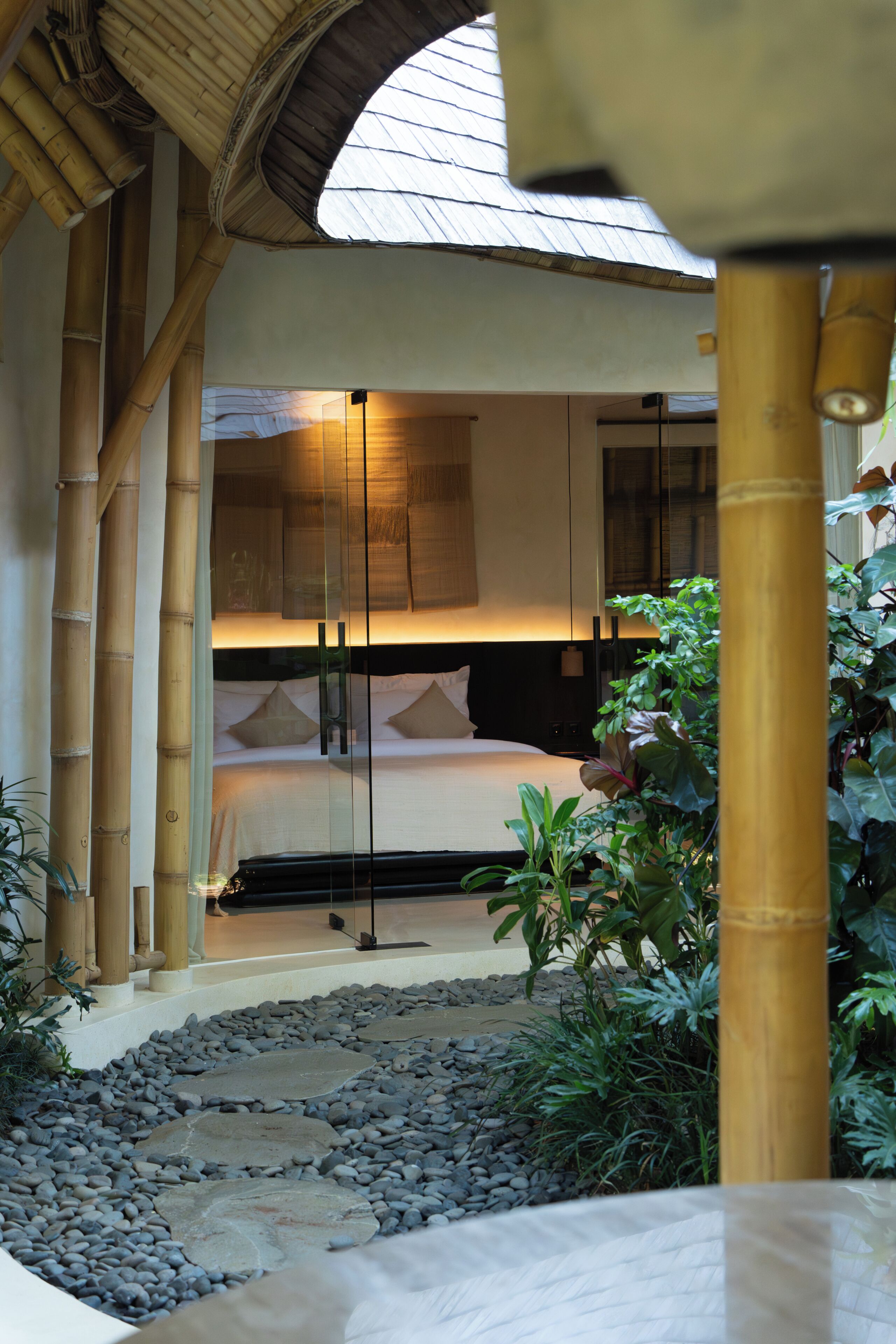 A room with a bed, a large window, and bamboo elements.