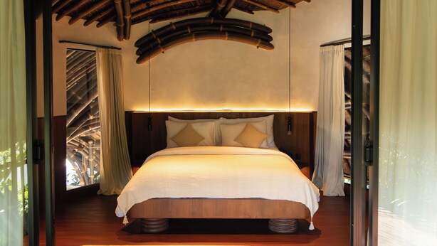 A room with a bed, wooden ceiling, and a view through a window. - Kaymana (Pecatu)