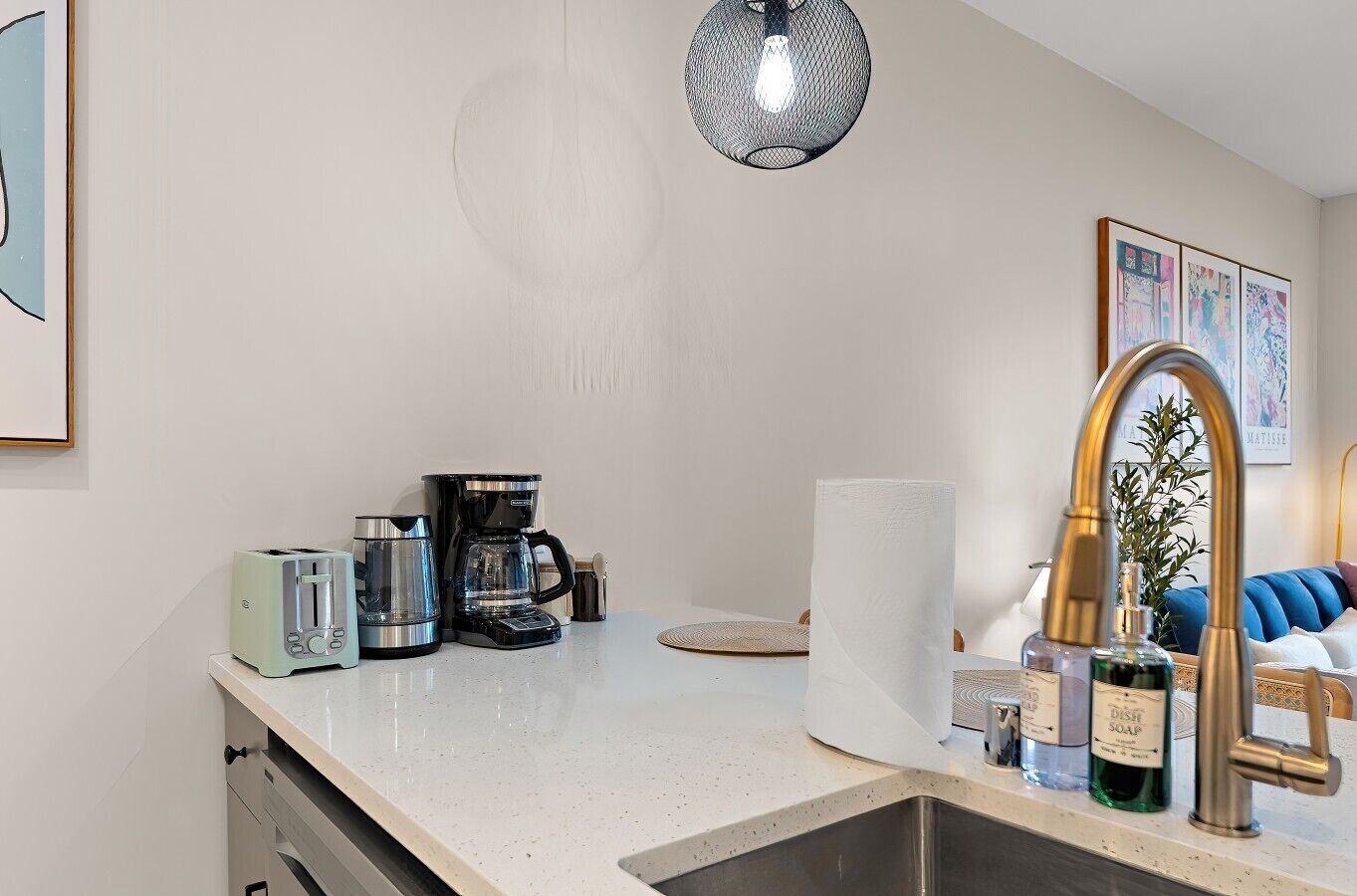 A kitchen with a toaster, coffee maker, and sink.