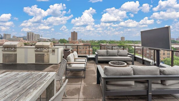 A rooftop terrace with outdoor seating, a grill, and a large screen. - Modern 1BR Near Downtown | Walkable City Stay (Minneapolis)