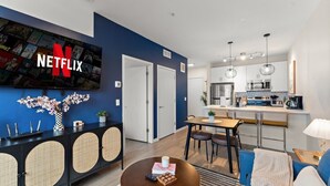 A modern living room with a dining area, kitchen, and a TV mounted on the wall displaying the Netflix logo. - Modern 1BR Near Downtown | Walkable City Stay (Minneapolis)