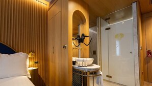 A hotel room with a bed, a round bathroom vanity, a mirror, and a shower area. - Kate Hotel Special Class (Istanbul)