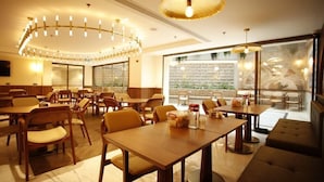 A restaurant with wooden tables and chairs, a large chandelier, and a view through the windows. - Kate Hotel Special Class (Istanbul)