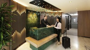 A reception desk with a green marble top, a wooden bench, and a vertical light panel on the left. - Kate Hotel Special Class (Istanbul)