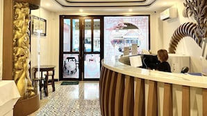 A reception area with a wooden reception desk, a large decorative wall piece, and a patterned floor. - Sunny Beach Hotel (Patong)