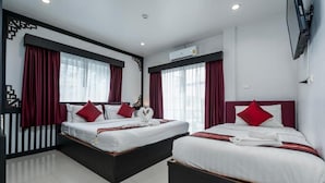 A hotel room with two beds, red curtains, white bedding, and an air conditioning unit. - Sunny Beach Hotel (Patong)