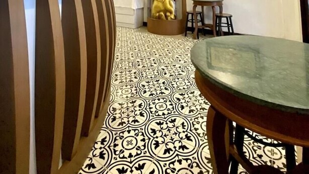 A reception area with a patterned floor, a reception desk, a decorative column, and a framed picture on the wall. - Sunny Beach Hotel (Patong)