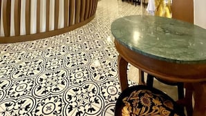 A reception area with a patterned floor, a reception desk, and a wall with a decorative design. - Sunny Beach Hotel (Patong)