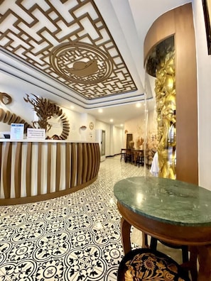 A reception area with a patterned floor, a reception desk, and a wall with a decorative design.