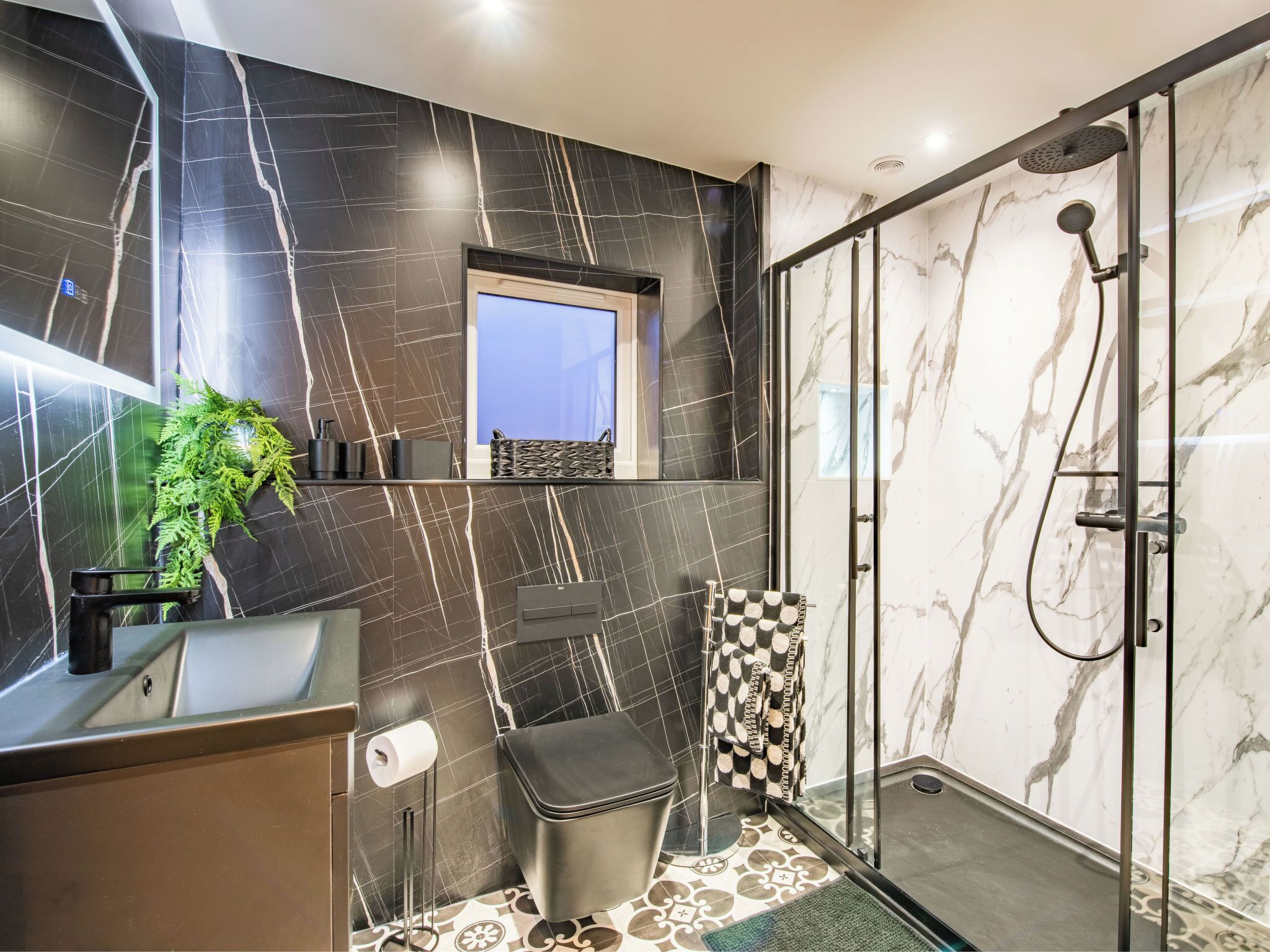 A modern bathroom with a glass shower enclosure, a sink with a mirror, and a toilet.