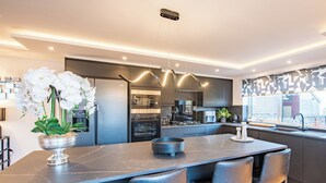 Une cuisine moderne dotée d’un îlot central, de tabourets de bar, d’un réfrigérateur et d’un four à micro-ondes.