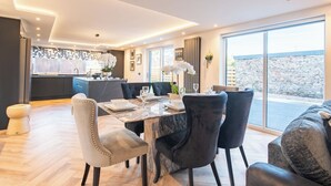 Un espace de repas moderne avec une table en marbre, des chaises recouvertes d’un tissu noir et blanc, et une vue sur l’extérieur.