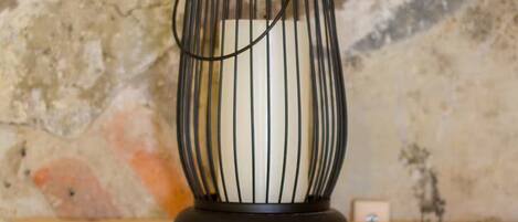 Un chandelier noir est posé sur une étagère en bois, adossé à un mur à la texture particulière.
