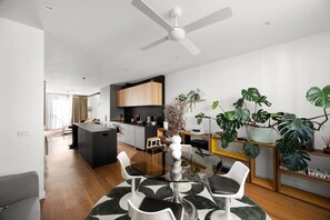 Eine moderne Küche mit einer zentralen Kochinsel, einem Essbereich mit Glastisch und einem Deckenventilator.