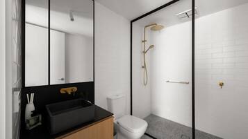 A modern bathroom with a black sink, a toilet, a shower with a gold showerhead, and a large mirror.