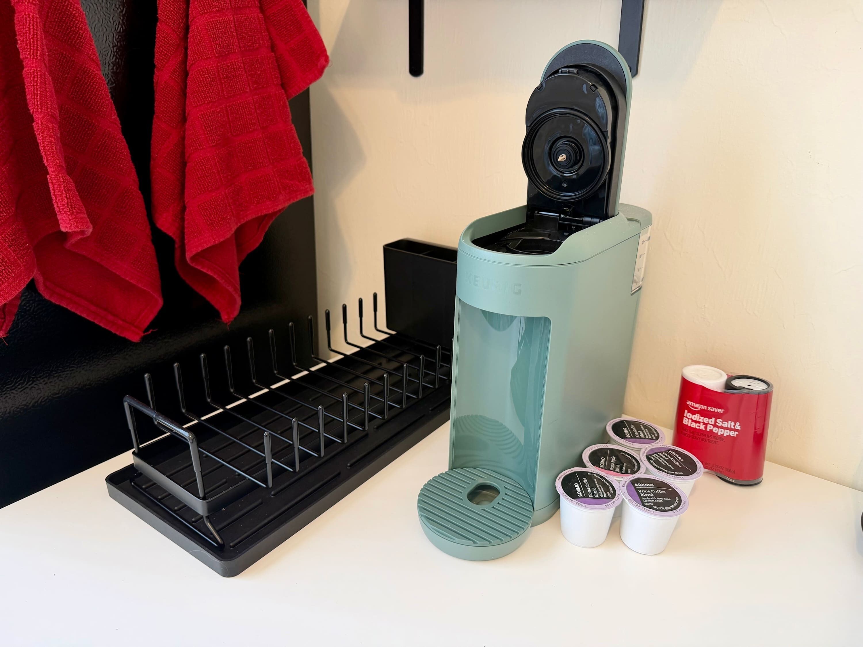 A Keurig coffee maker, a coffee pod holder, and a can of Amazon Saver Iodized Salt & Black Pepper.