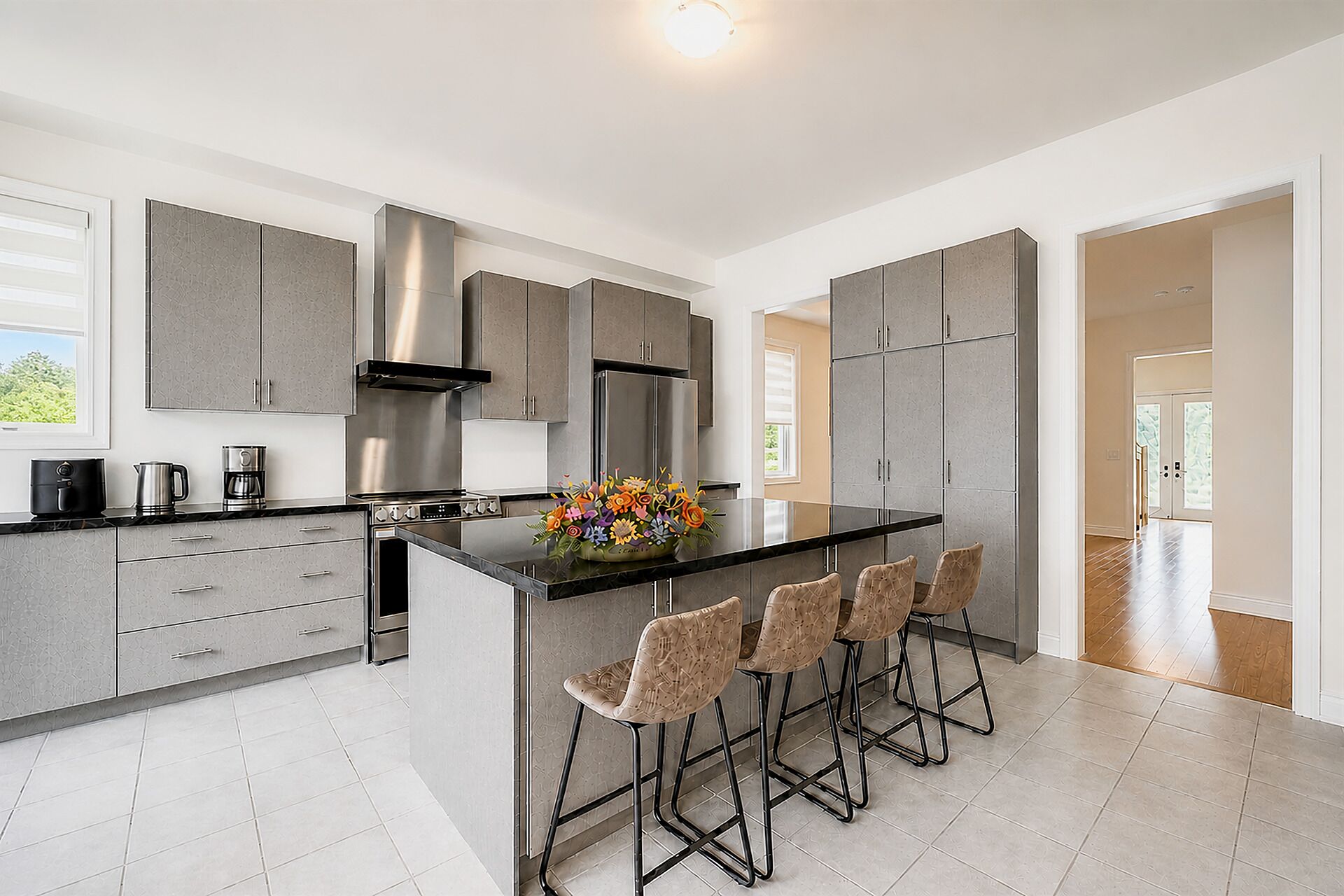 A modern kitchen with grey cabinets, a central island with bar stools, and a coffee maker on the counter.
